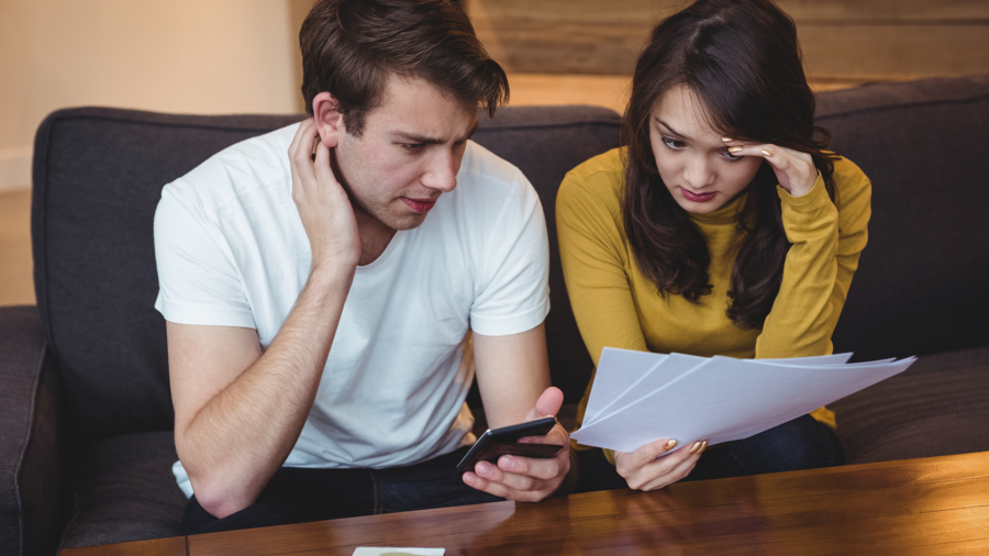 casal-sentado-no-sofa-discutindo-documentos-financeiros-na-sala-de-estar1